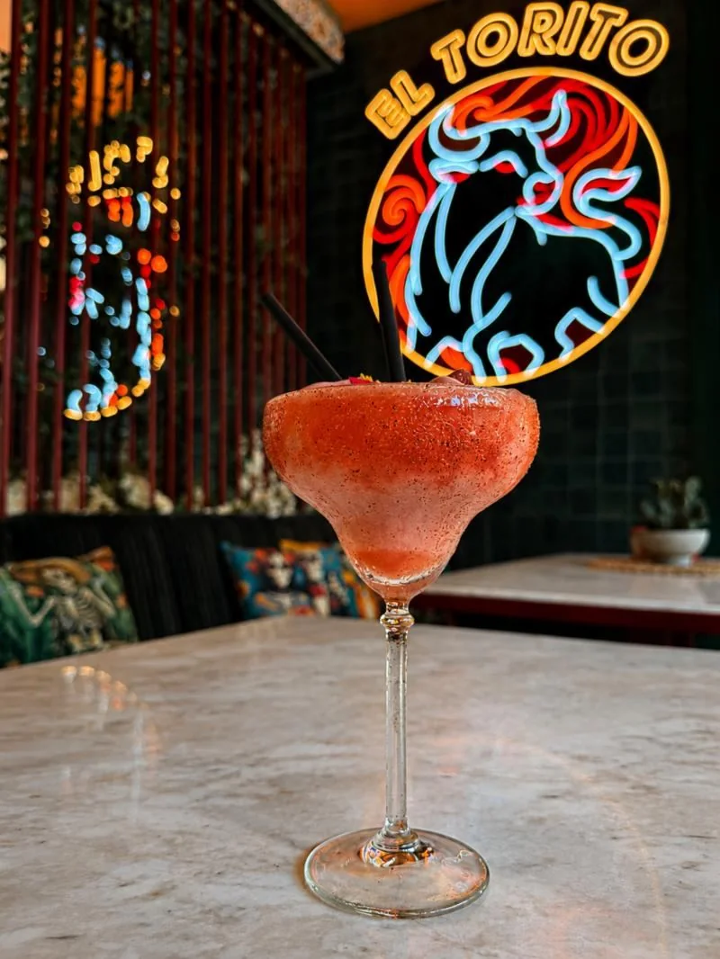 Margarita frozen în fața emblemei neon El Torito